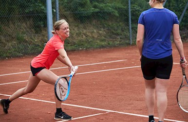 Kvinde har det sjovt på tennisbanen.jpg
