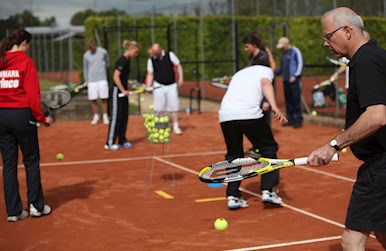 Mand sjonglere med tennisbolde på tennisbane.jpg
