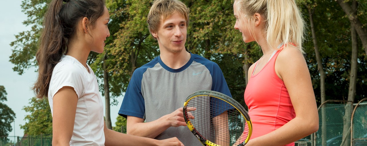 Unge tennisspillere snakker ved nettet