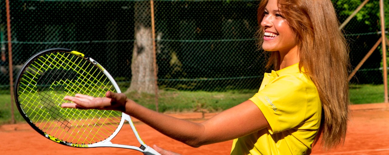 Tennispige jonglerer med orange tennisbold