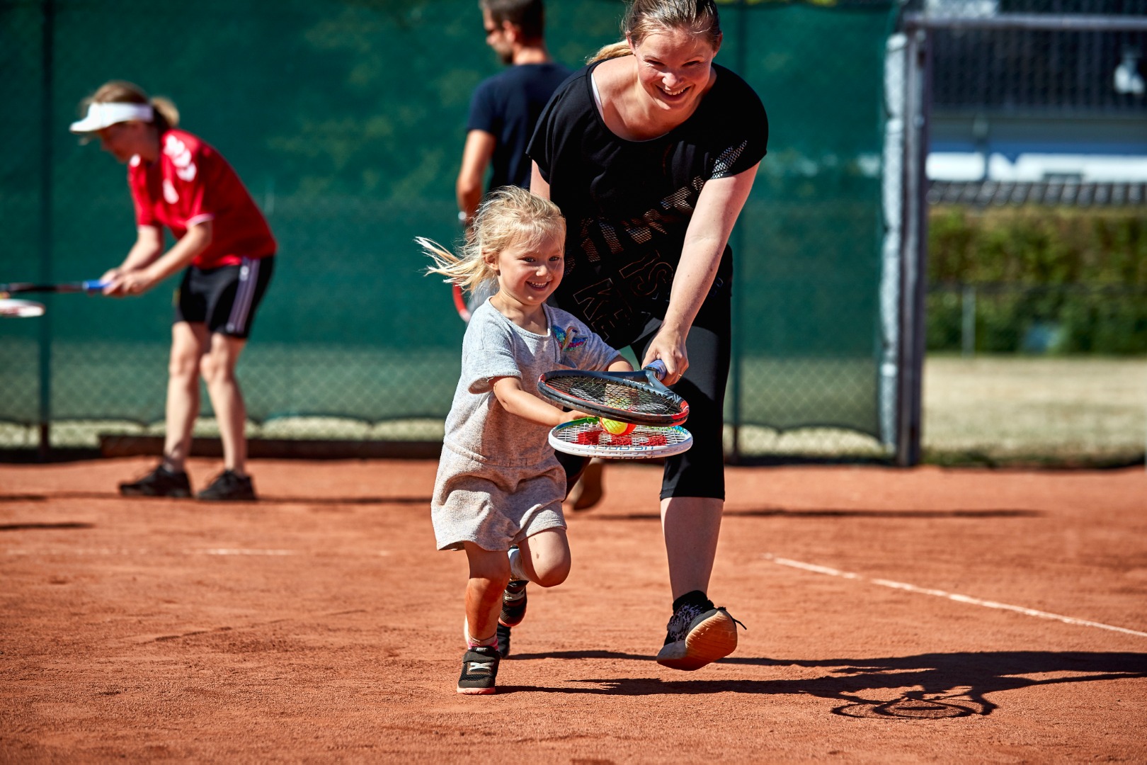 Mor og datter løber med tennisbold.jpg